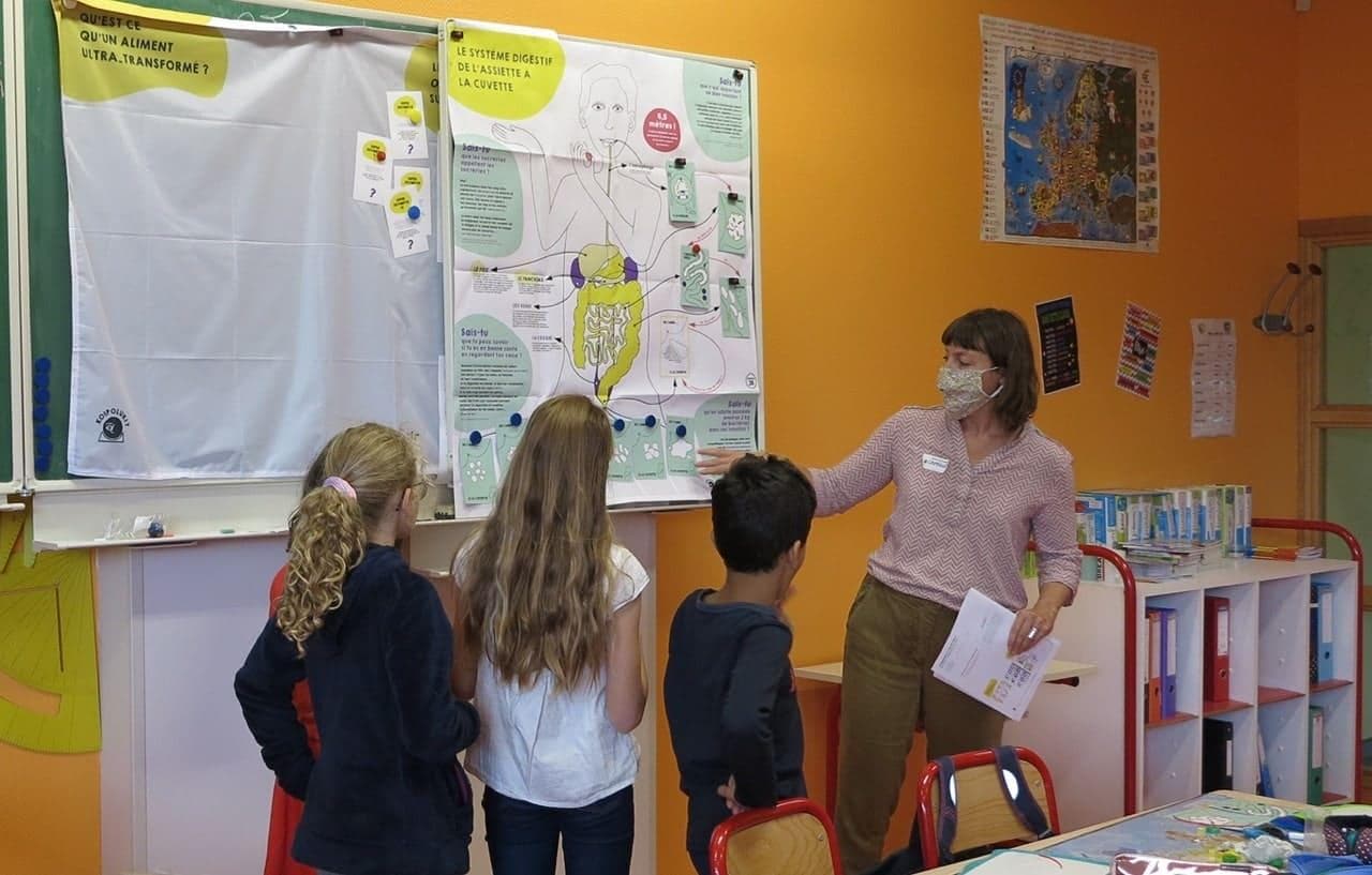 Une affiche sur le système digestif sur le tableau sert de base de discussion avec les élèves