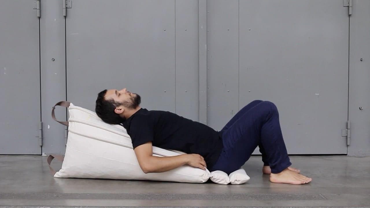 un jeune homme se masse le dos allongé sur le gros rouleau